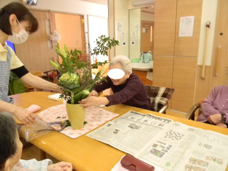 スタッフと入居者が花を活ける活動を行っており、レクリエーションの場面